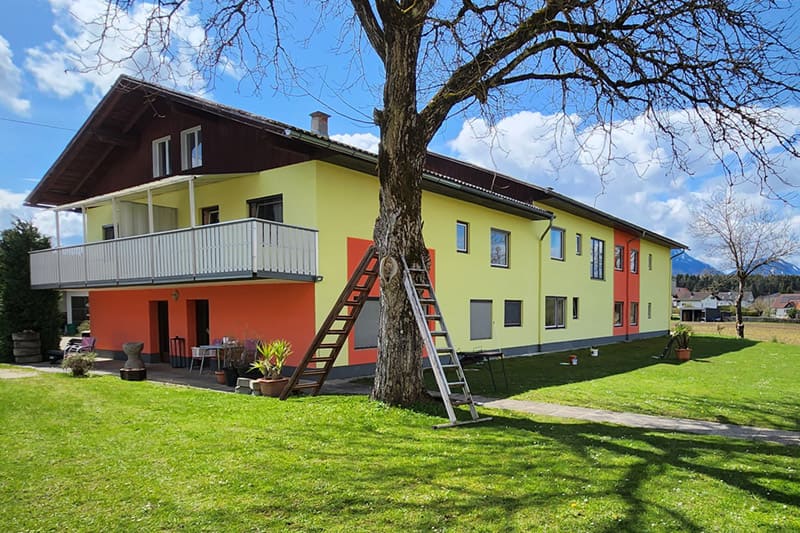 Neuer Fassadenanstrich für ein großes Wohnhaus in Gelb- und Orangetönen