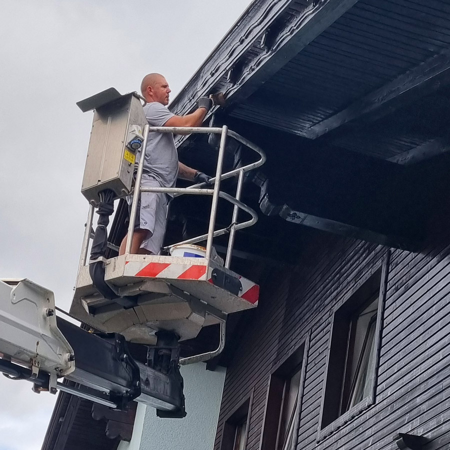 Maler Achim Sturm beim Streichen der Untersicht eines Dachen