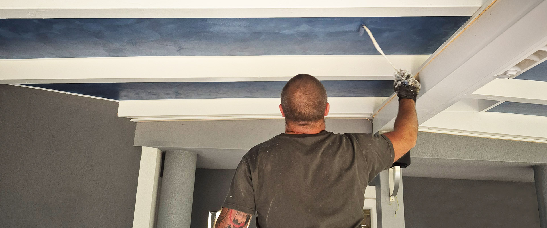 Maler Achim Sturm beim Streichen der Decke